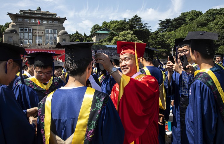 Con una túnica roja, Dou Xiankang ajusta la borla de un graduado durante su ceremonia de graduación en la Universidad de Wuhan.