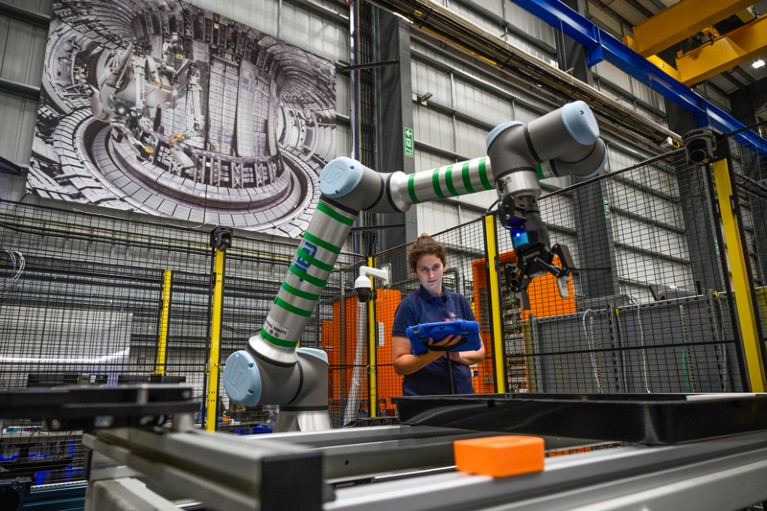 A female engineer operates a robotic arm.