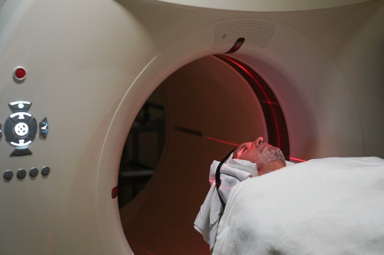 A patient lies on a bed about to enter a large, cylindrical scanner to get a PET scan