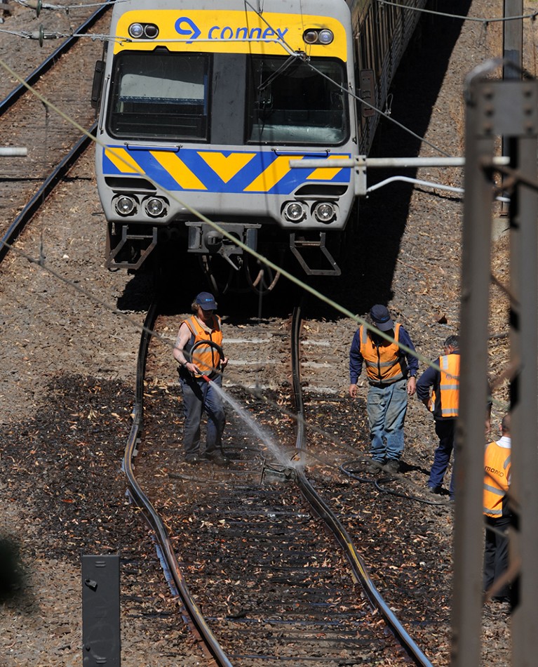 A train is stopped at in Melbourne, Australia, due to buckled train tracks from extreme heat that workers are cooling off.