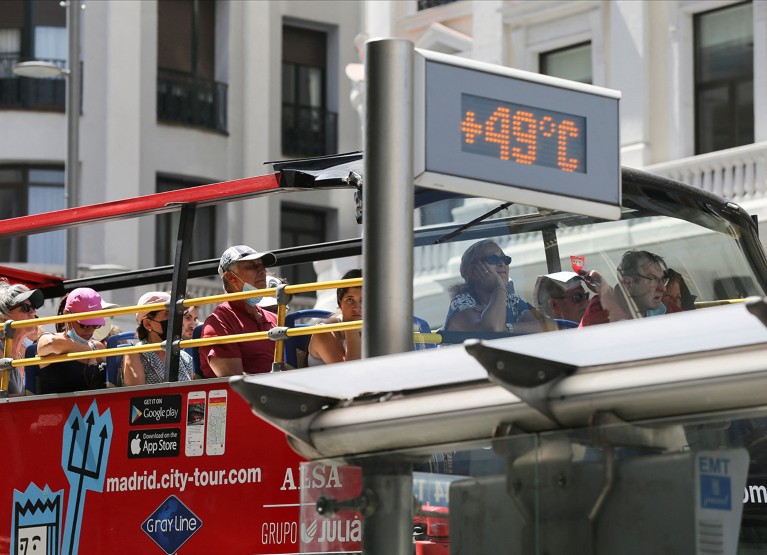 A tourist bus rides past a thermometer displaying 49 Celsius degrees (120 Fahrenheit) in Madrid, Spain.