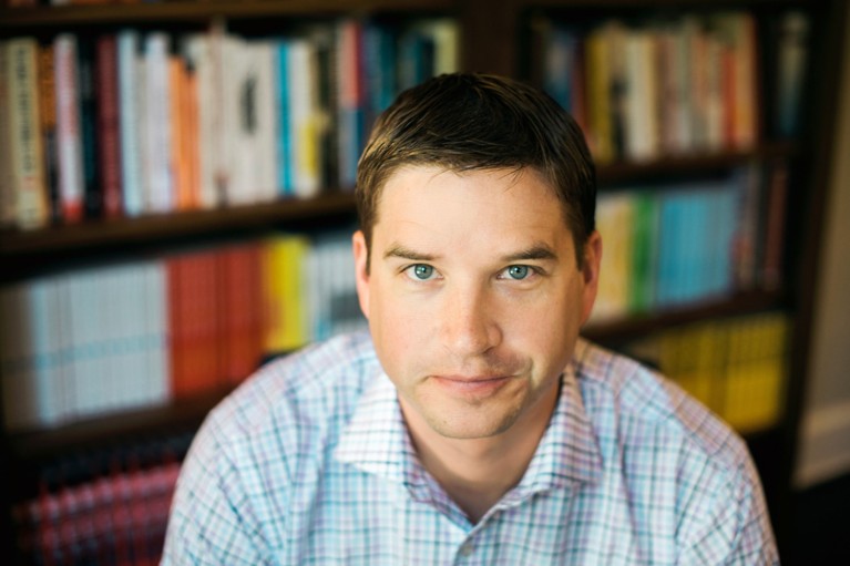 Portrait of Cal Newport photographed in front of some bookshelves