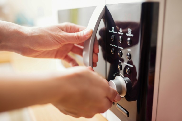 A close-up of hands operating a microwave