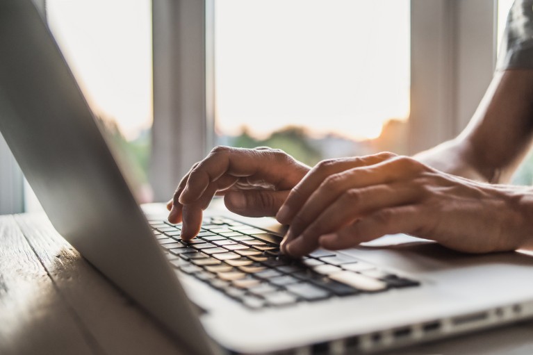 Close-up of hands typing on a laptop keyboard