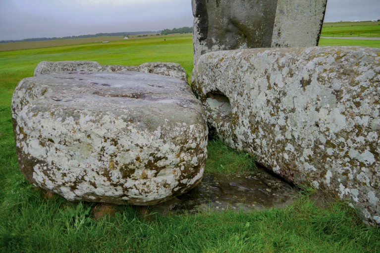 The Altar Stone at Stonehenge, almost completely submerged in the ground underneath two other oblong stones lying lengthways