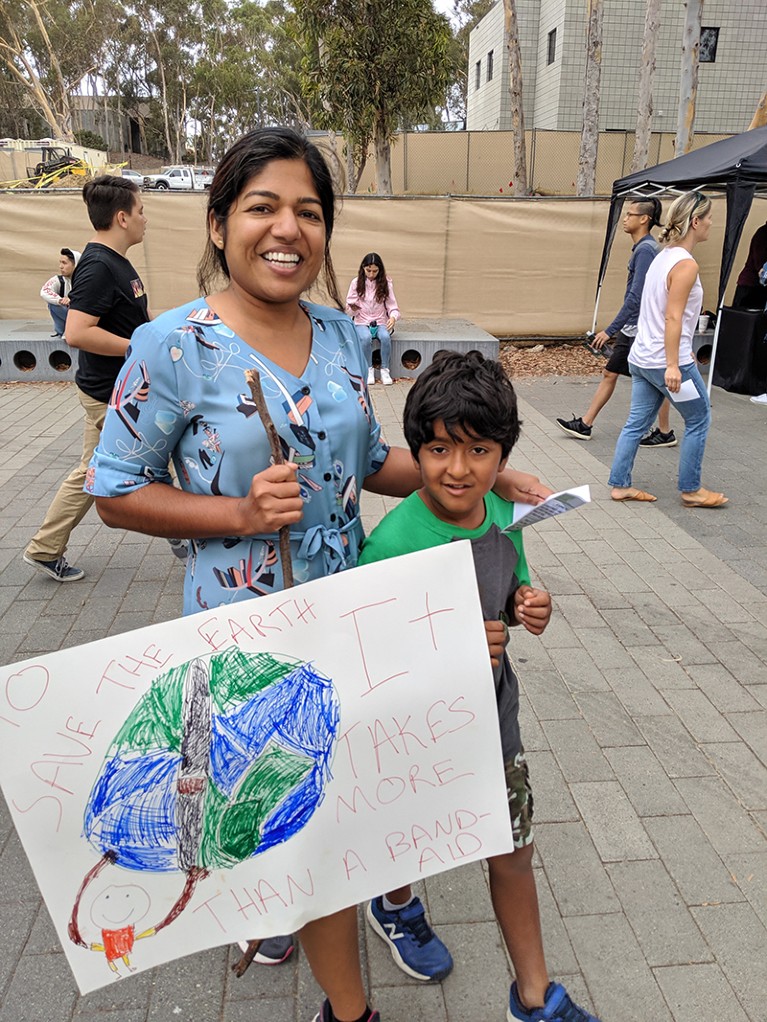 Jyoti Mishra and her son hold a placard that reads "To save the earth it takes more than a band-aid"