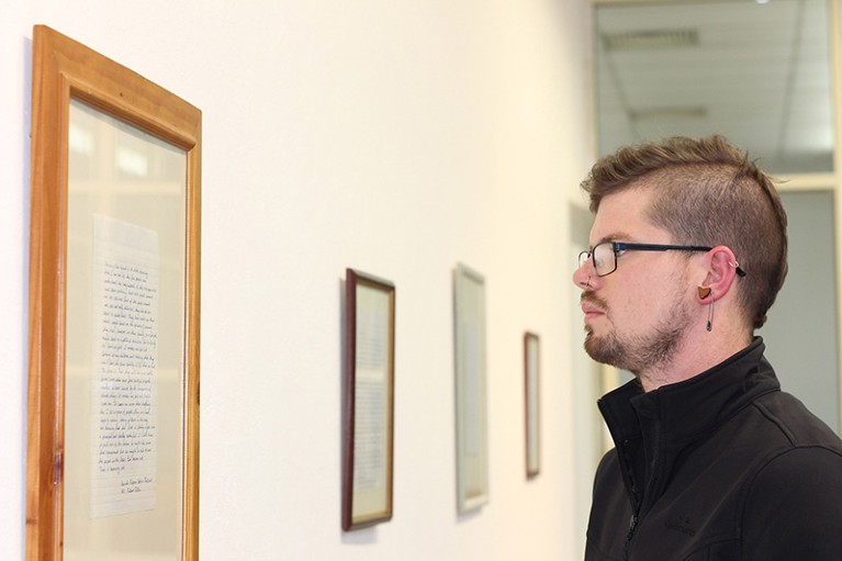 Joe Duggan is seen looking at a framed letter on a wall of an exhibition