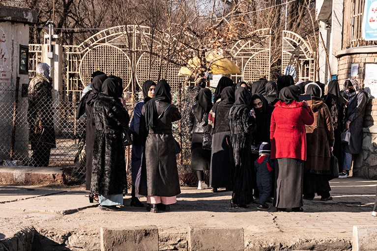 A group of female university students stand outside the gates of a University in Kabul