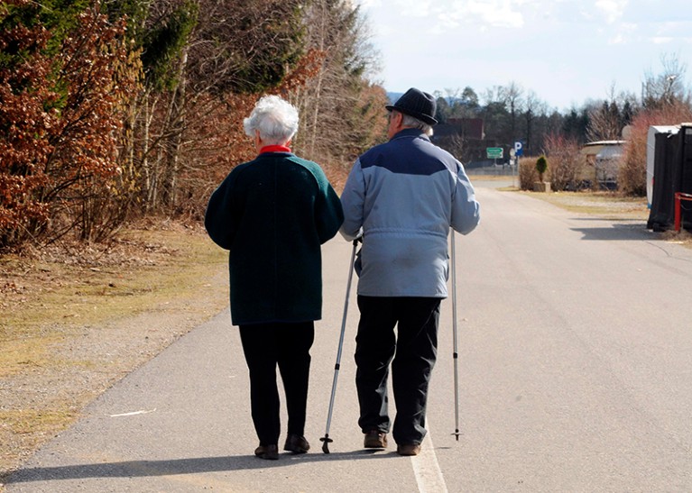 An elderly woman and a man walk down a street together