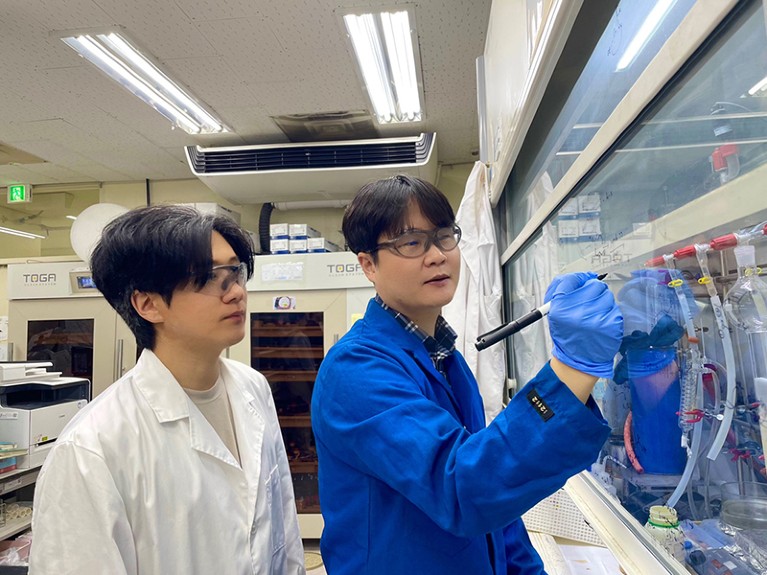 Semin Lee and Seung Hwang Cho writing on a fume hood screen in a lab