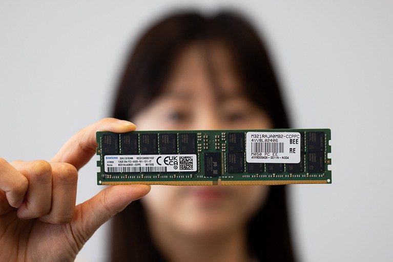 A woman holds a Samsung hard drive between thumb and forefinger