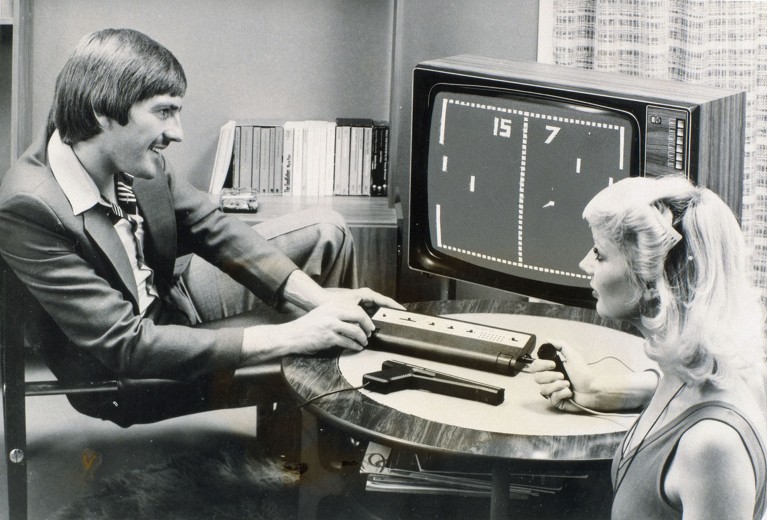 Black and white photograph of a man and a woman playing the computer tennis game Pong.