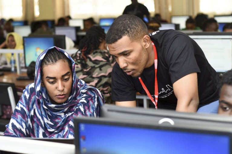 Participants in an AI learning workshop hosted by Deep Learning Indaba look at a computer