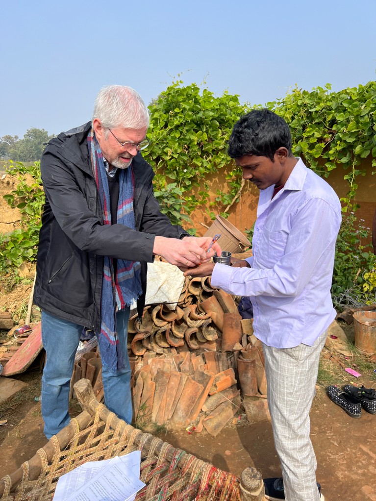 Wim van Brakel passes medicine to a patient in India