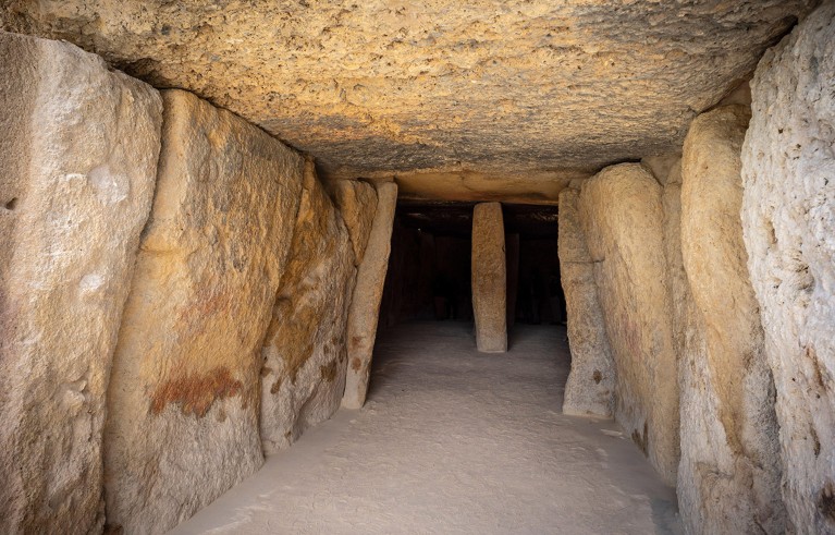 The interior of the Dolmen of Menga, its walls and ceilling built of stone slabs, with a central pillar.