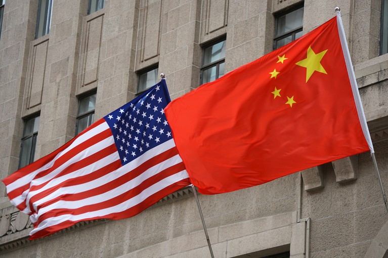 The national flags of the United States and China on flagpoles outside the Fairmont Peace Hotel in Shanghai, China.