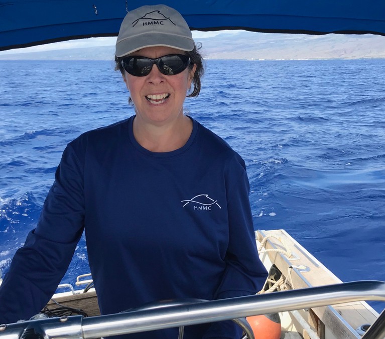 Woman with beige cap driving a boat.