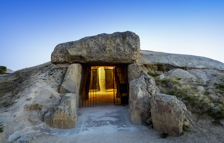 Exterior view of the entrance to the Dolmen of Menga, with the interior illuminated.