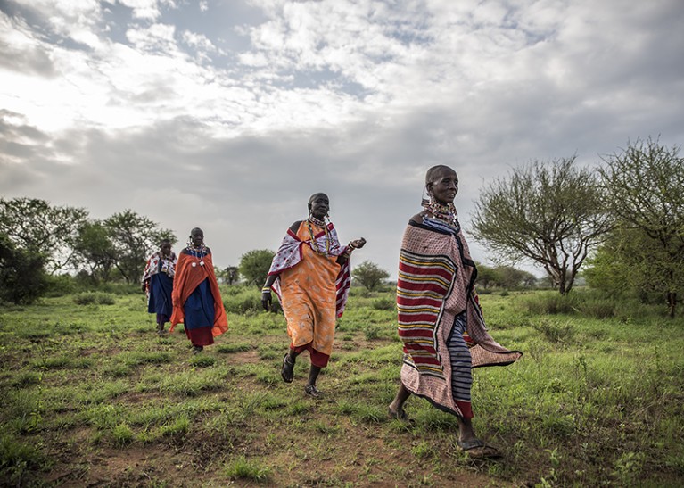 Maasai women are seen walking through greenery