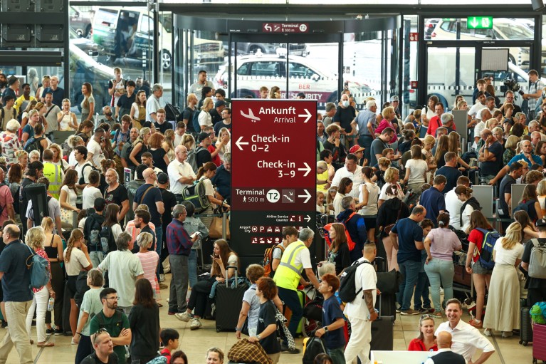 A large group of travellers wait at Berlin Brandenburg Airport