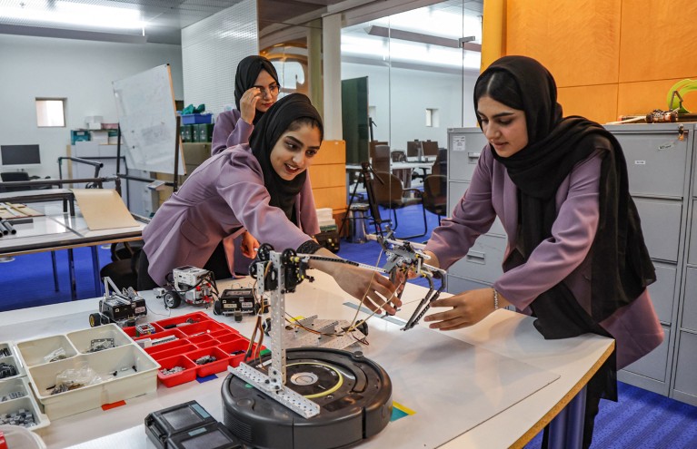 Three female robotics students work in a lab