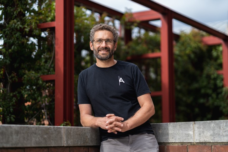 A portrait of Ilan Gur resting on a brick wall outside The British Library