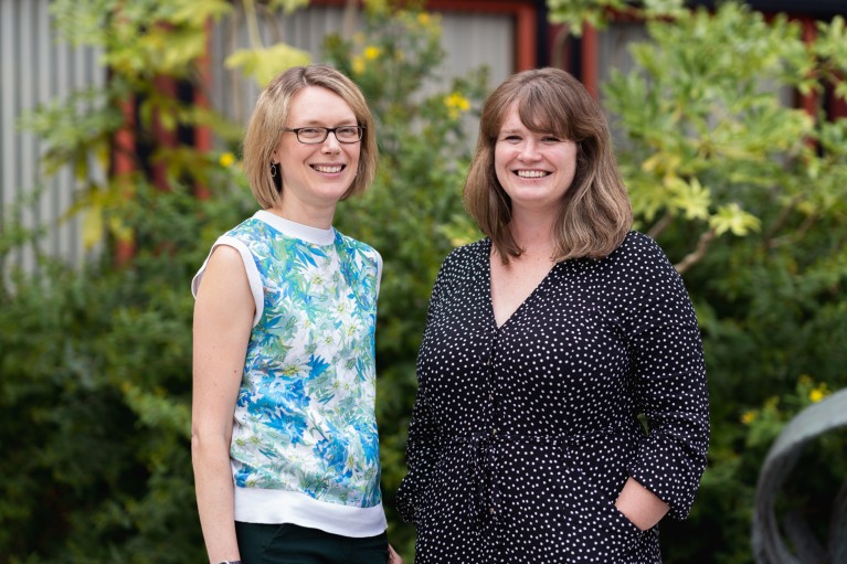 A portrait of Sarah Bohndiek and Gemma Bale stood in front of some bushes outside The British Library