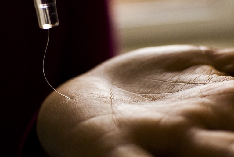 Closeup of a very thin bendy wire pressing into a human palm