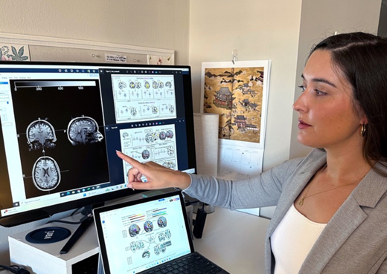 Natalie Osbourne points at brain scans on a computer in a busy office