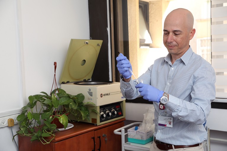 Amir Minerbi looks down as he pipettes a sample into a tube in a bright office