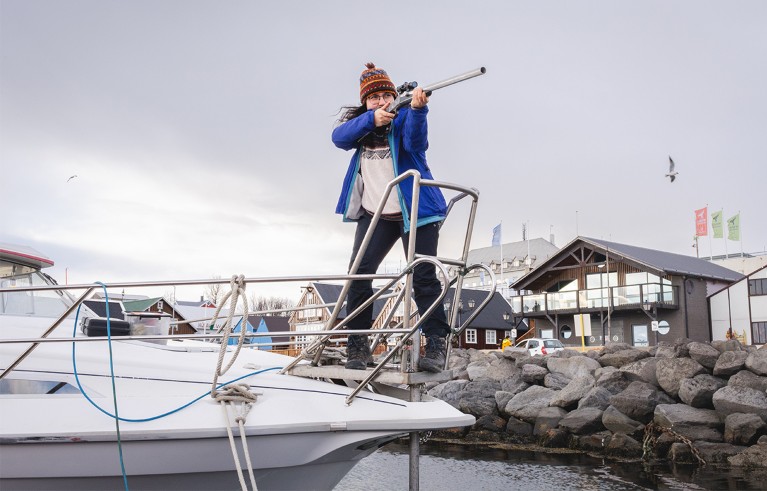 Yakamoz Kizildas points a biopsy gun for whales from the deck of a ship.