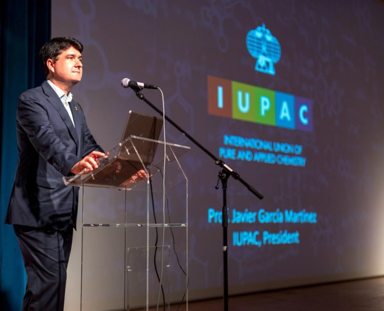 Javier Garcia Martinez standing at a lectern giving a speech at a conference.