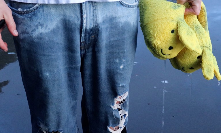 A person, sporting ripped jeans and clutching a ragged yellow plushie, is shown from the waist down.