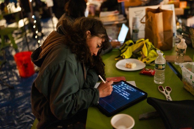 Jessica Metzger escreve fórmulas em seu tablet em uma mesa.