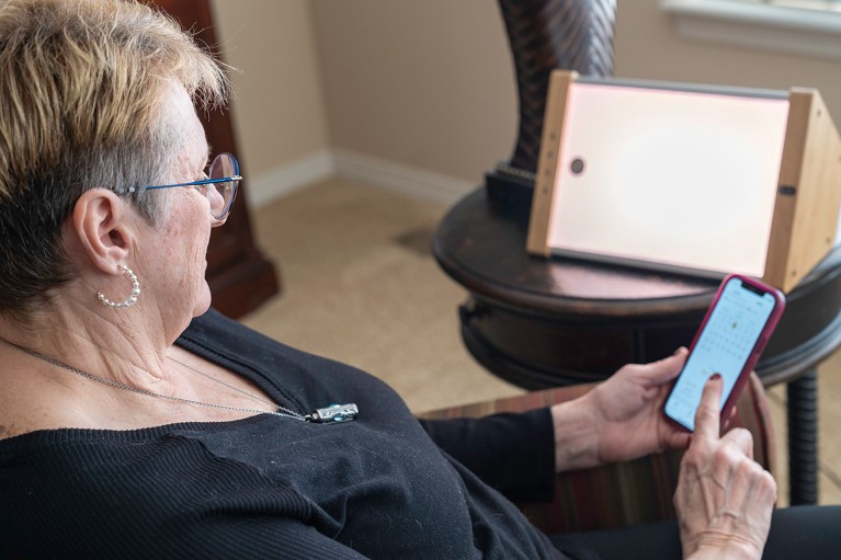 A woman uses a smartphone while sat next to an EVY Light.