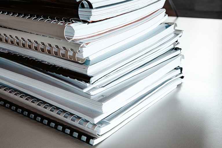 Stacks of bound papers lie on a desk