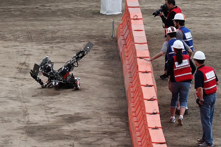 A robot falls backwards during its first run at a DARPA challenge.