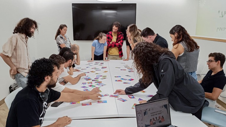 Jewish and Arab Technion students gather round a table covered in coloured cards while participating in a program entitled “Shared Living on Campus”