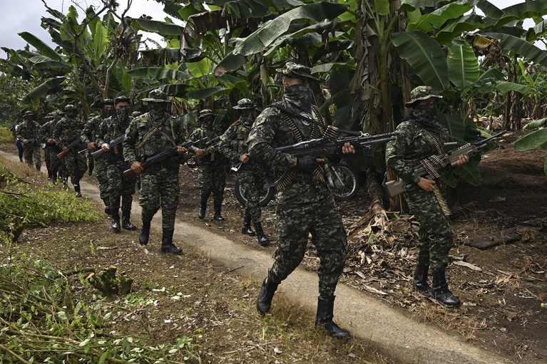 Armed soldiers of the FARC dissident group Segunda Marquetalia march on a farm in a rural area of Colombia in 2024.