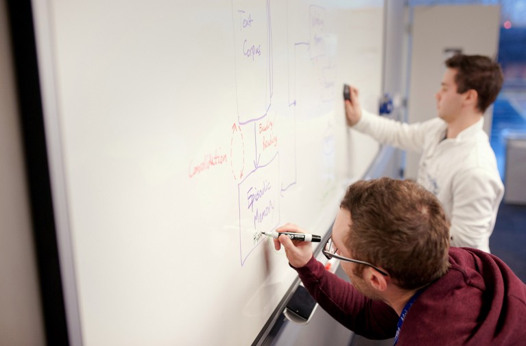 Research scientists write out AI loop diagrams on a whiteboard.