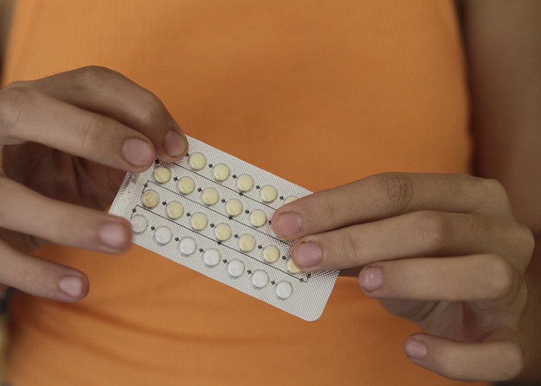 A woman's hands hold a pack of birth control pills