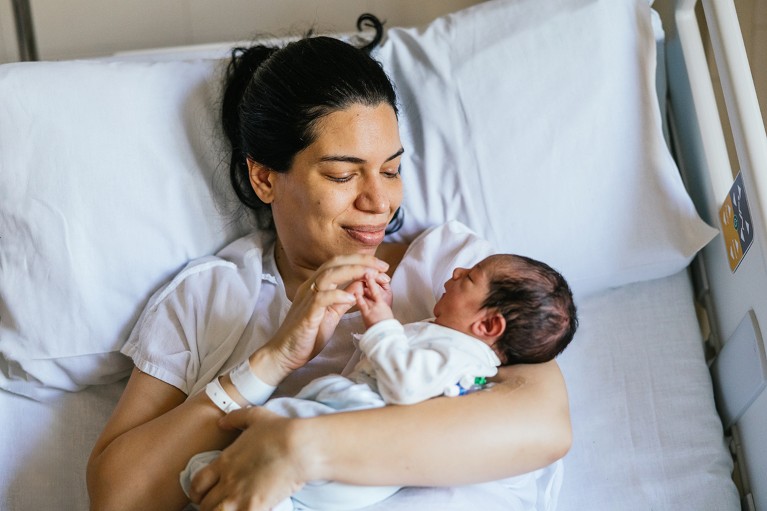 A woman in a hospital bed holds a newborn baby.