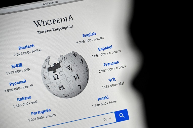 A close-up image shows the front page of the Wikipedia website on a laptop screen.