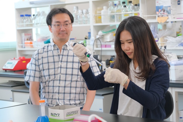 A professor supervises an intern working in the lab at Kumamoto University