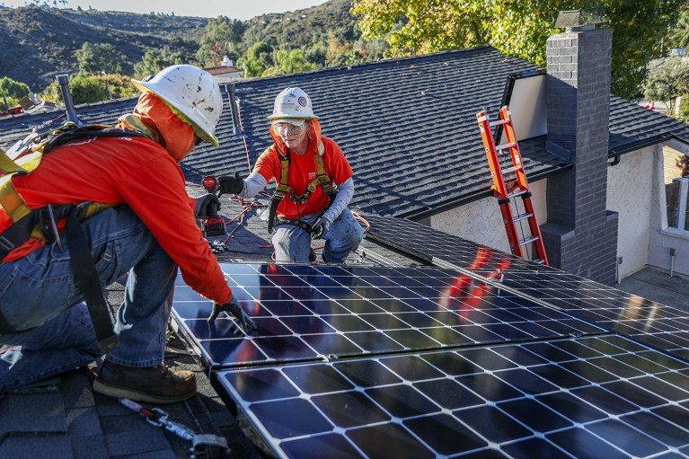 Two workers install solar panels on the rooftop of a home in Poway, California, U.S.