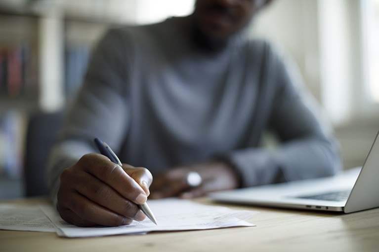 A close up photo of a man's hand writing on a piece of paper