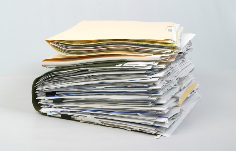 A pile of file folders overstuffed with paper documents.