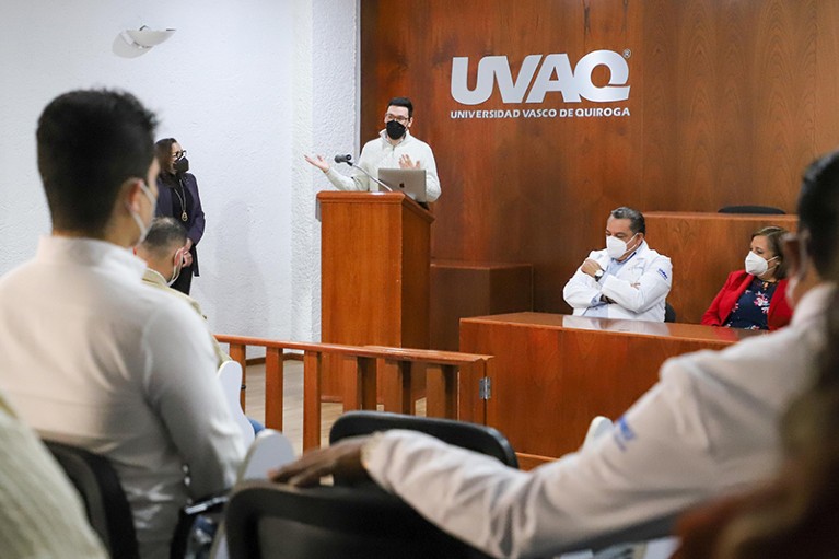 David Posner stands at a lectern while giving a talk at UVAQ medical school.