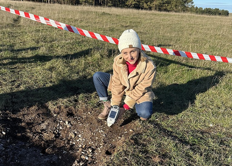 Olena Melnyk crouches down while testing soil