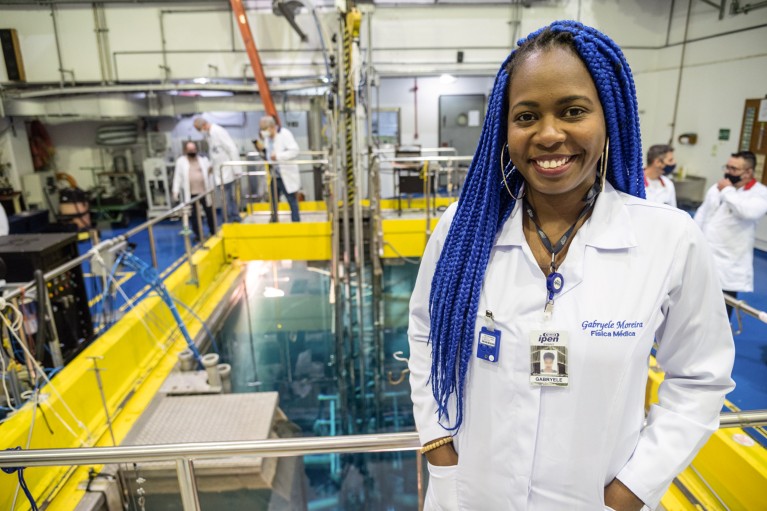 Gabryele Moreira posing for a portrait in front of a nuclear reactor pool at Brazil's first nuclear reactor facility